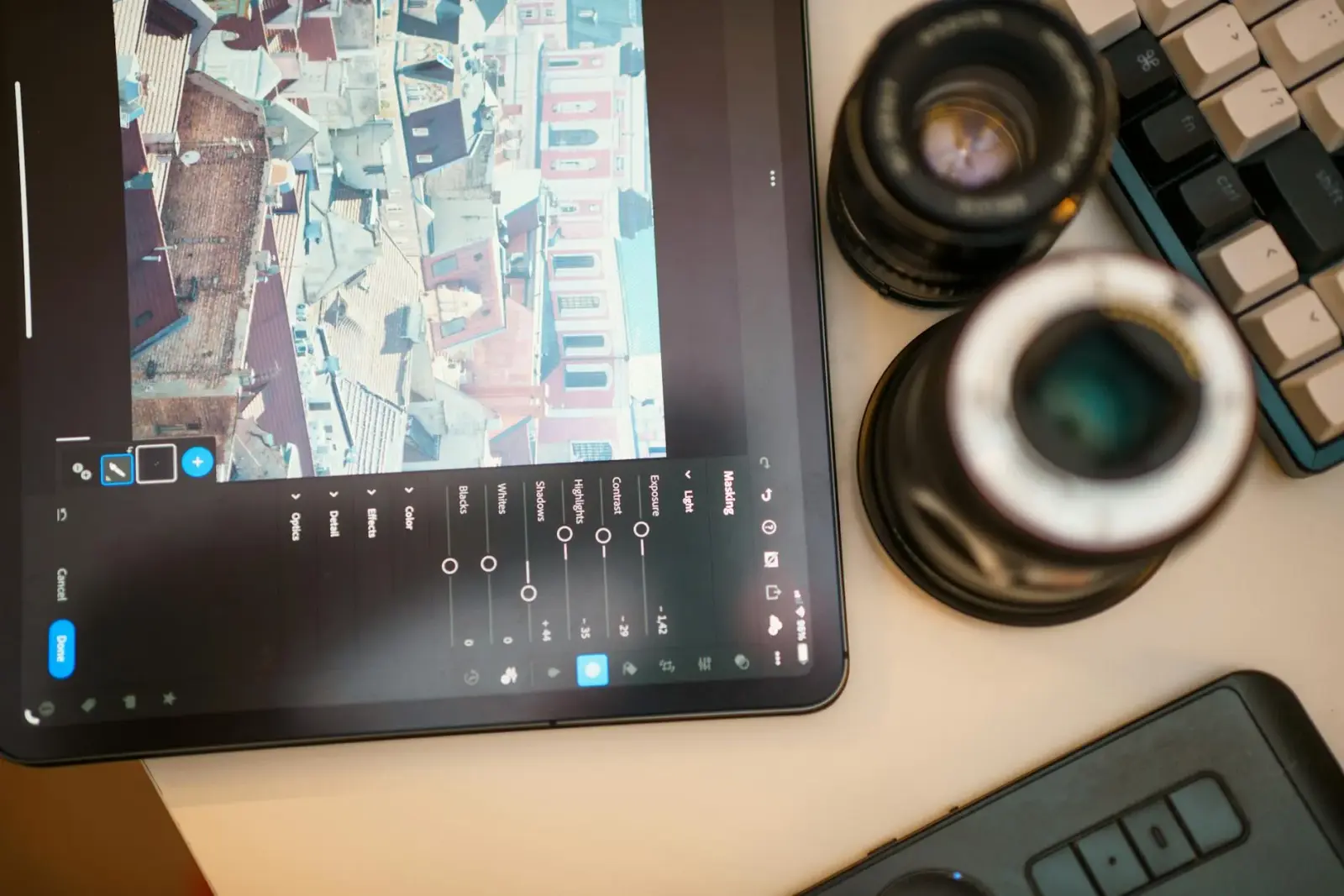 Close-up of a student's hands adjusting Anki settings on a tablet amidst a messy dorm room desk.
