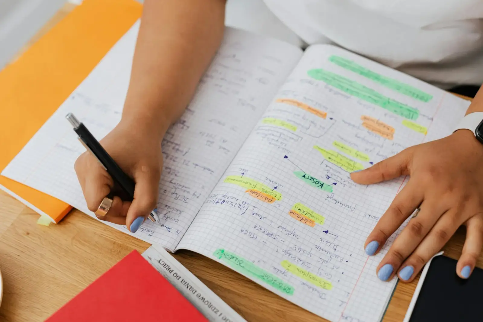 Close-up of a student's hands highlighting notes for the bar exam on a messy desk.