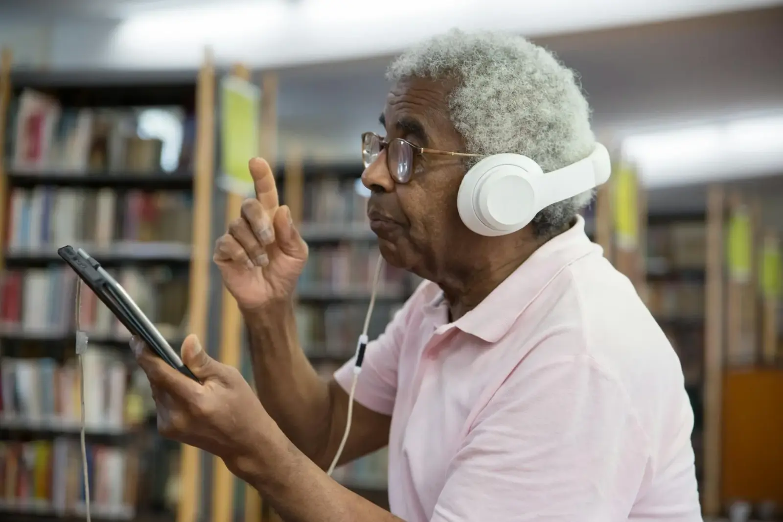 Close-up of student's hands interacting with a tablet to create digital flashcards in a modern library setting with cool blue lighting.