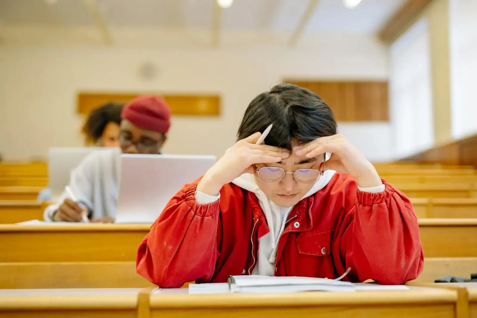 Close-up of student's hands typing notes on a tablet in a modern library lecture hall